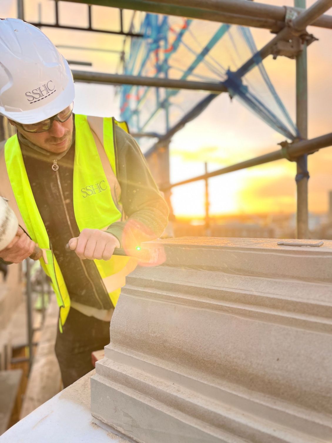 SSH craftsperson shaping the moulded profile of a stone cornice on site